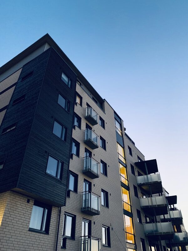 Modern multifamily building exterior after renovation with dark cladding and balconies